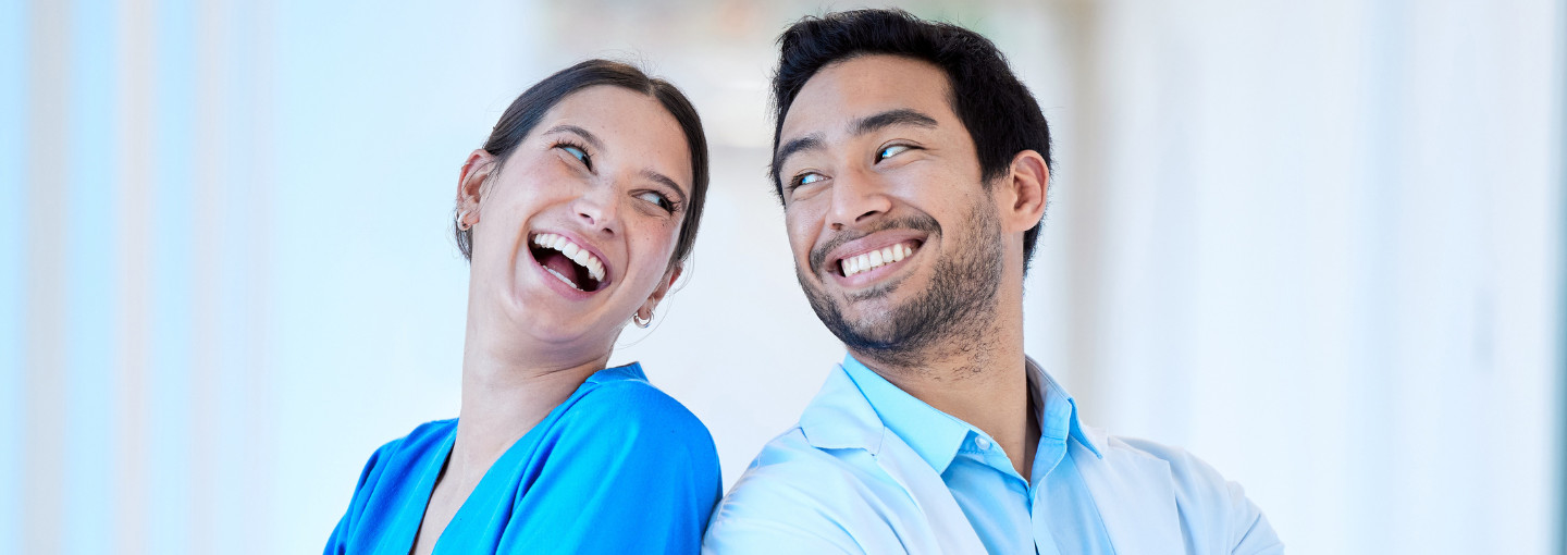 A female and male dentists looking at each other over their shoulders